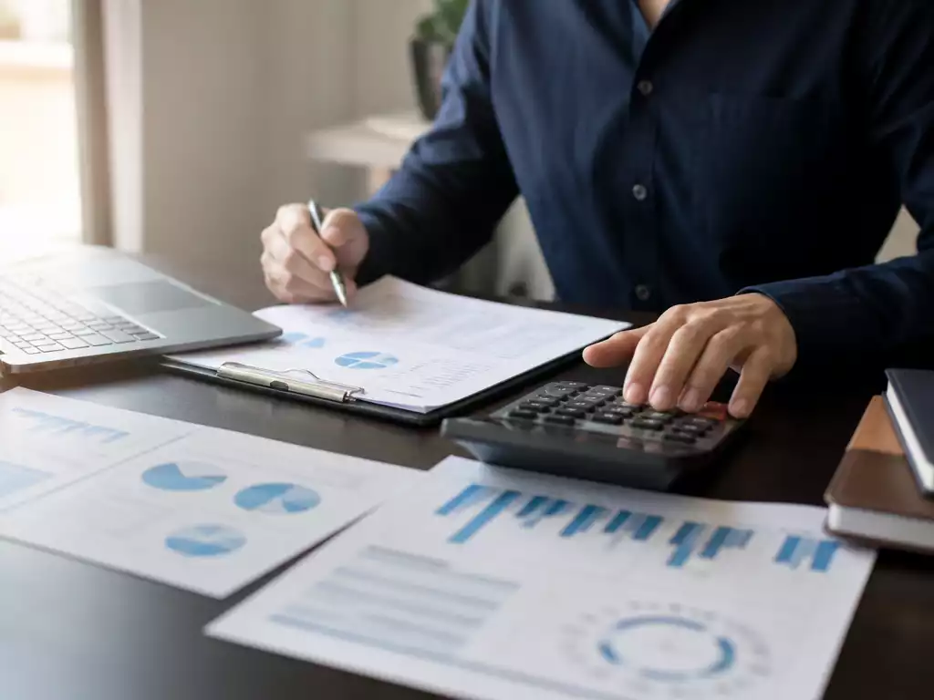 Person reviewing financial documents and calculations on a desk
