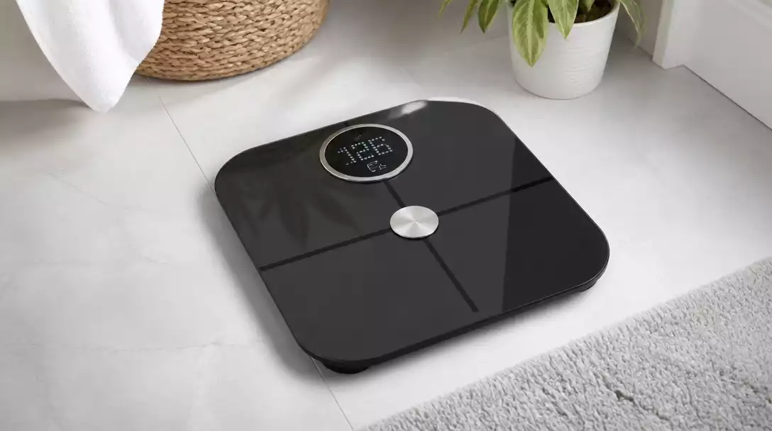 Modern Taylor smart scale with a digital display on a clean bathroom floor, showing weight and body fat percentage, no text, no words, no typography, clean image