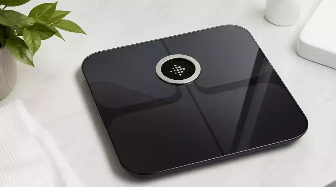 Fitbit Aria Scale displaying weight and body composition on a clean bathroom counter