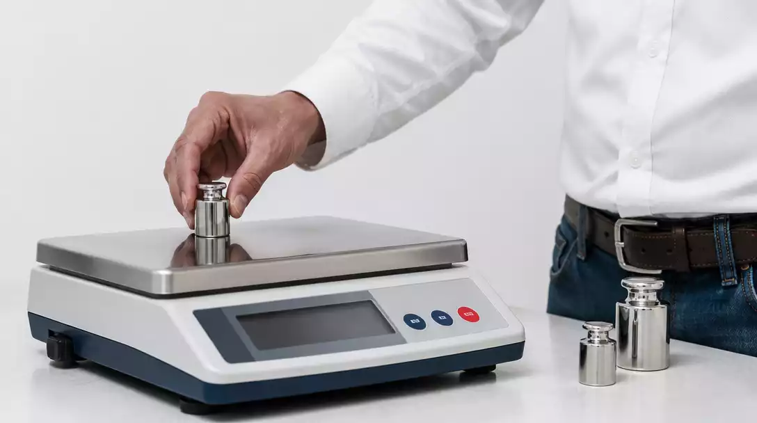 Person calibrating a digital scale on a flat surface