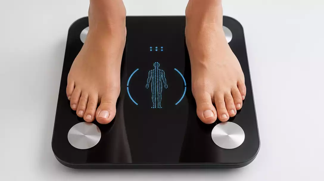 Modern smart bathroom scale displaying body composition data, with a person's feet on it