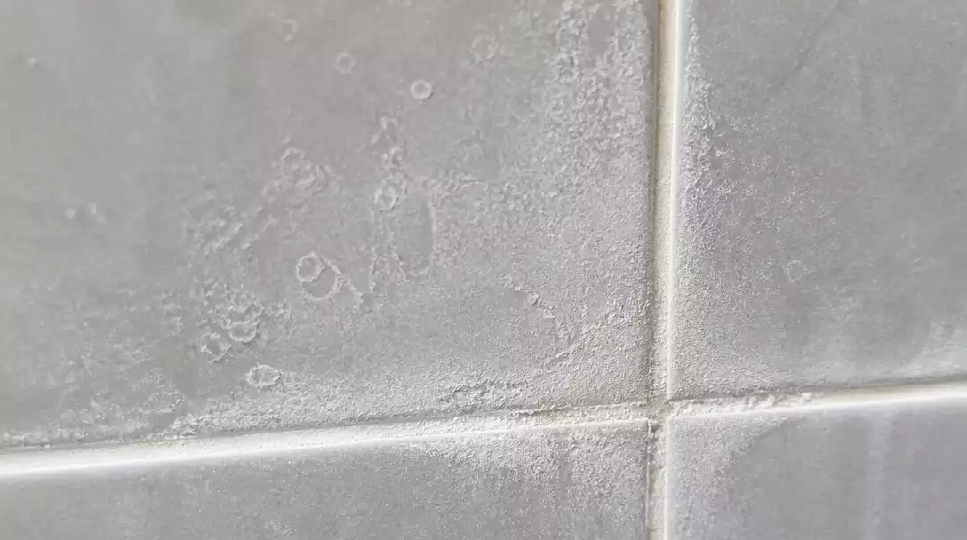 Bathroom tiles with visible limescale buildup, illustrating the problem of hard water deposits